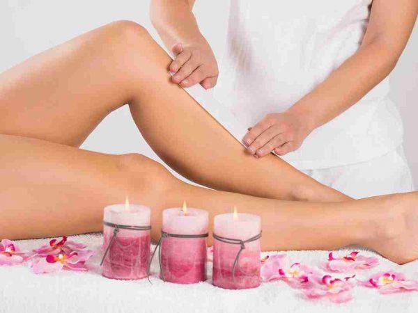 Beautician Waxing Woman's Leg At Salon